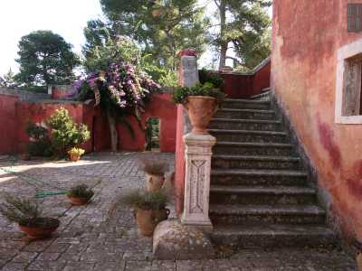 L�atrio dell�abitazione dove spiccano i vivaci colori di fiori, piante e vasi in terracotta disposti sulla scala che conduce agli interni